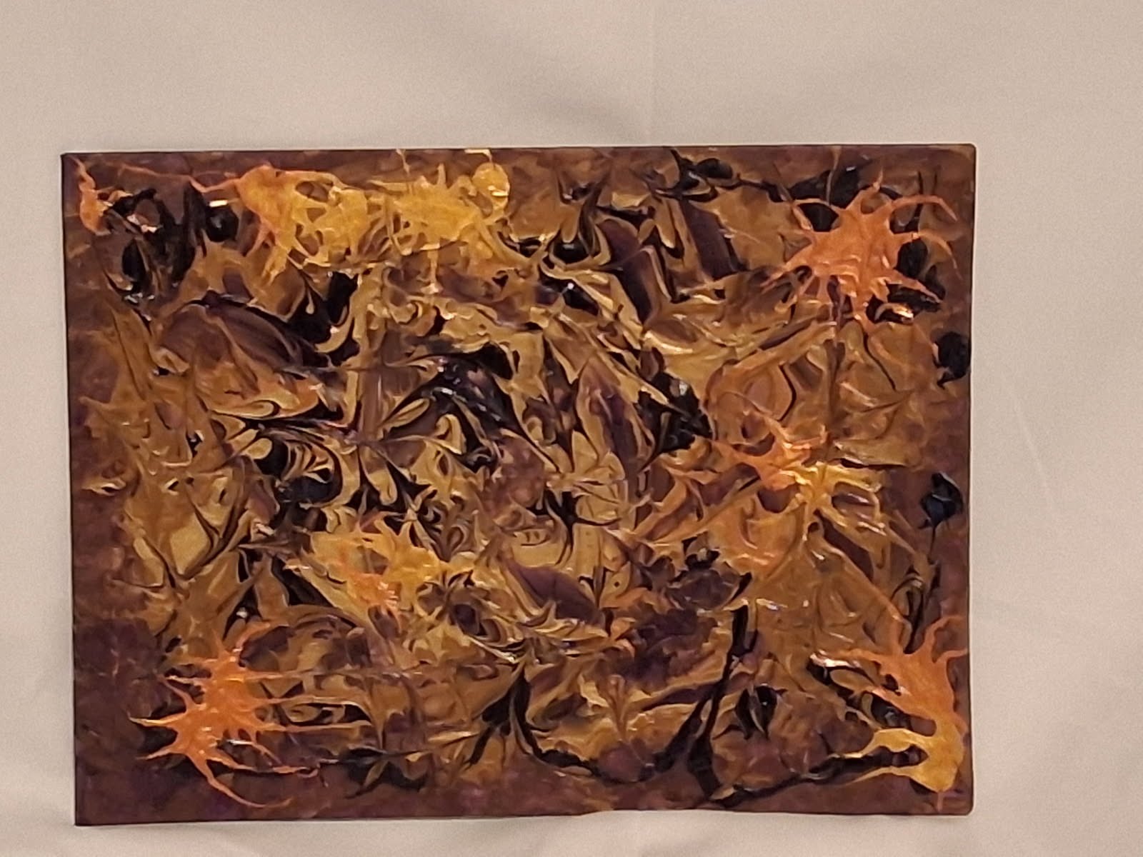 Textured brown and gold abstract artwork photographed on a light background